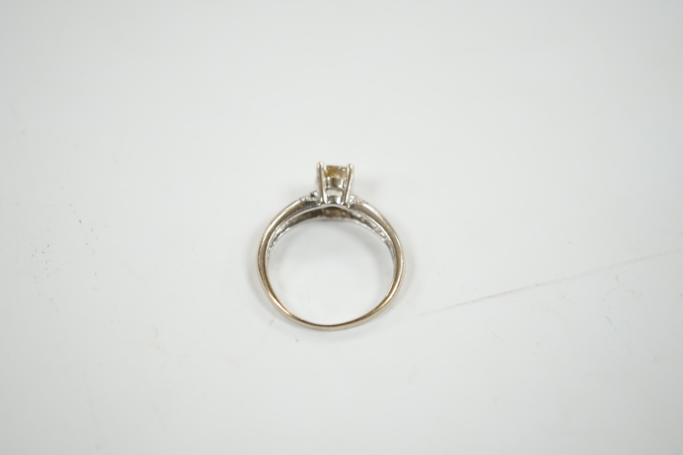 A 750 white metal and single stone oval cushion cut diamond ring, with four stone diamond chip set shoulders, size K, gross weight 3.3 grams.
